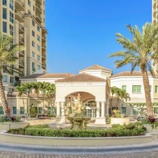 A stunning view of a luxurious residential complex featuring elegant architecture and beautifully landscaped outdoor areas.