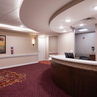 A hotel reception area with a curved desk and carpeted floors.