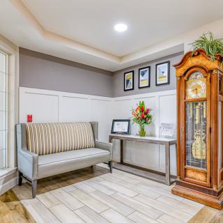 A modern living room interior featuring a bench, grandfather clock, and decorative artwork.