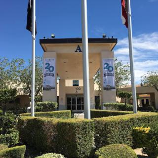 A well-maintained building with flags and banners against a clear blue sky.