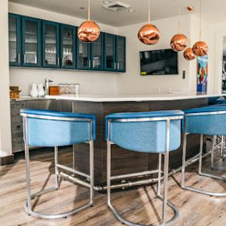 A stylish modern kitchen bar featuring sleek blue chairs and elegant copper pendant lights.