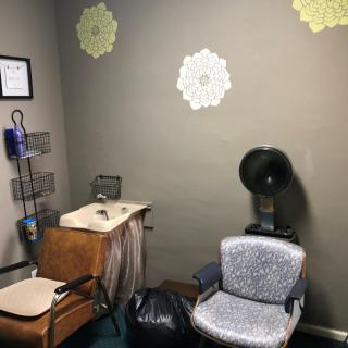 A cozy vintage-style hair salon corner with a dryer chair and decorative wall accents.
