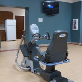 A modern gym with an exercise bike and a wall-mounted television in a spacious, empty room.