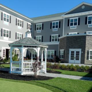 A well-maintained residential building with a white gazebo and lush green lawn.