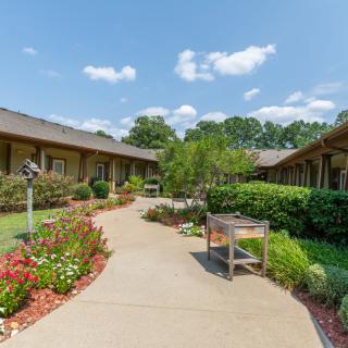 A scenic view of a pathway surrounded by gardens in a residential setting on a sunny day.