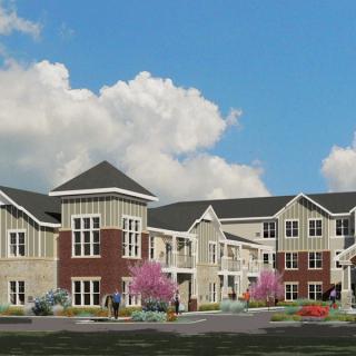 A modern residential building with a landscaped front yard under a partly cloudy sky.