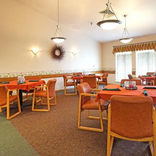 A cozy dining area with multiple tables and chairs, adorned with warm lighting.