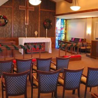 Interior view of a chapel with an altar and rows of chairs.