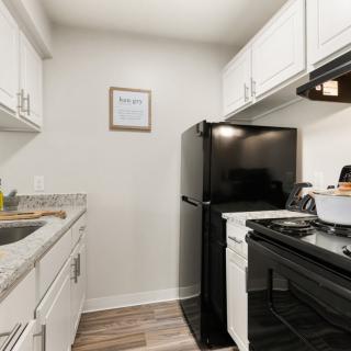 A modern, compact kitchen with white cabinets and black appliances.