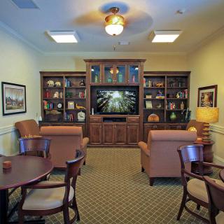 A cozy living room featuring comfortable seating, a large bookshelf, and a television.