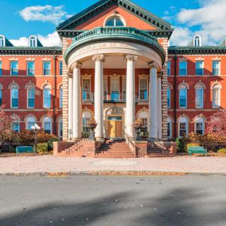 A historic red-brick building with large white columns on a university campus.