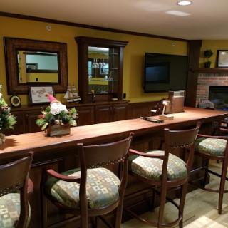 A cozy home bar area featuring wooden furniture, decorative mirrors, and a television for entertainment.