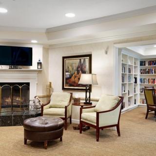 A cozy living room with a fireplace, comfortable seating, and a bookshelf filled with books.