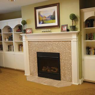 A cozy living room with a fireplace surrounded by bookshelves and artwork.