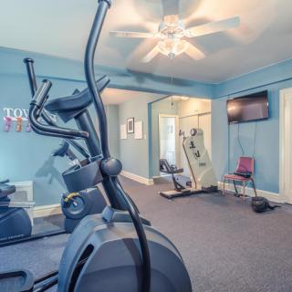A home gym featuring an elliptical machine and a wall-mounted TV.