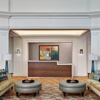 A modern hotel lobby with a reception desk, stylish seating, and decorative artwork.