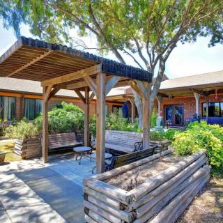 A peaceful garden area featuring a wooden pergola, benches, and lush greenery.