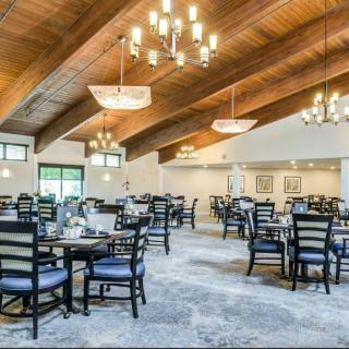 Spacious restaurant interior with elegant lighting and neatly arranged tables and chairs.