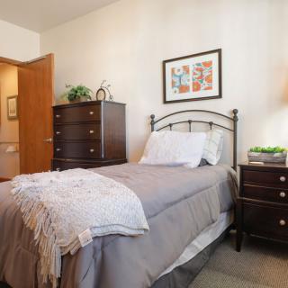 A cozy bedroom with a single bed, decorated with stylish furniture and artwork.