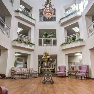 A spacious atrium with elegant lounge furniture, balconies, and a central chandelier.