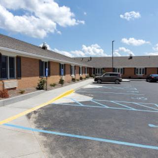 A view of a motel with a parking lot under a partly cloudy sky.