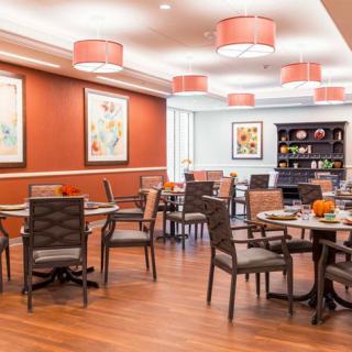 A well-decorated dining area with tables and chairs, featuring artwork on the walls and stylish ceiling lights.