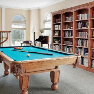 A stylish room featuring a billiards table and bookshelves, combining leisure and study.