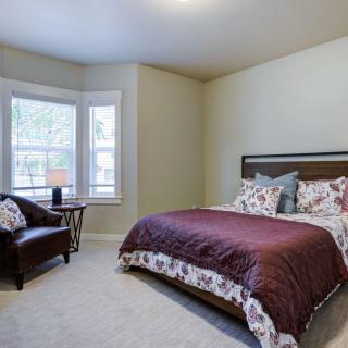 A cozy bedroom with a large bed, decorative pillows, and a comfortable chair by the window.