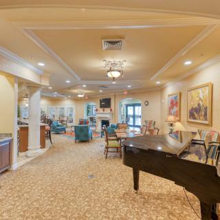 A spacious living room with a grand piano, comfortable seating, and elegant artwork.
