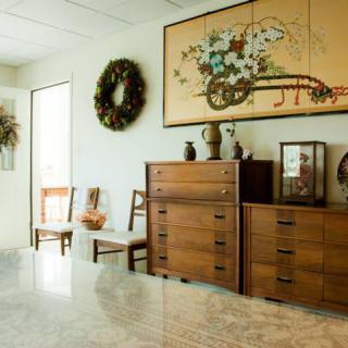 A vintage-style interior featuring wooden furniture, decorative wreaths, and framed artwork on the wall.