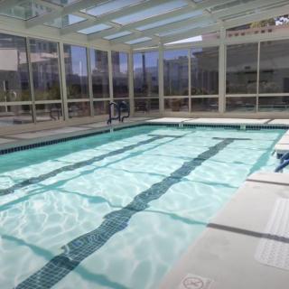 An indoor swimming pool with glass walls allowing natural light to enter.
