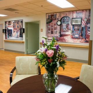 A cozy hospital lobby featuring a vase of flowers and artwork on the walls.