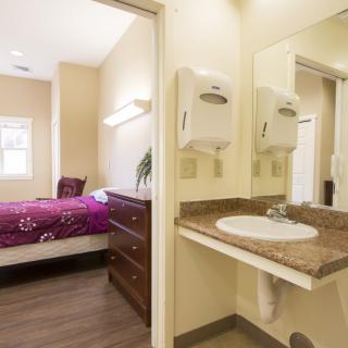 A cozy bedroom with an adjacent bathroom featuring a sink and mirror.