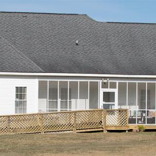 A house with a large screened porch and a wooden deck in the backyard.