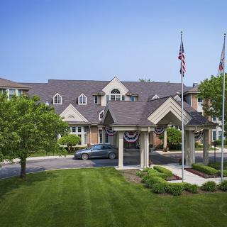 An elegant building with a well-maintained lawn and flags at the entrance.