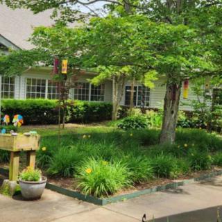 A beautifully landscaped garden outside a house with lush greenery and a paved pathway.