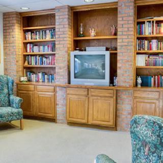 A cozy living room with built-in bookshelves, a television, and patterned armchairs.
