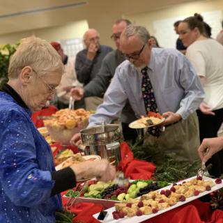 People serving themselves at a buffet during a social event.