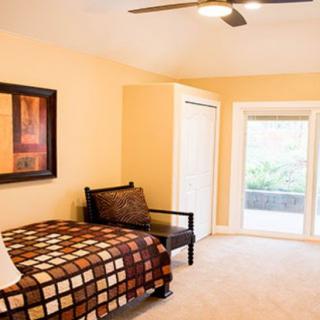 A cozy bedroom featuring a single bed, artwork on the wall, and a large window with a view.