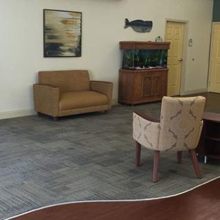 A comfortable waiting area with a sofa, chairs, an aquarium, and artwork on the wall.
