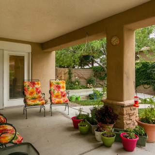 A cozy patio with colorful chairs and potted plants overlooking a well-maintained garden.