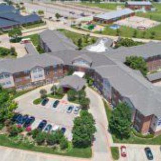 Aerial view of a large building complex with surrounding parking and landscaped areas.