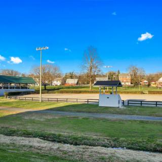 A sunny day at an outdoor baseball field with a scoreboard and surrounding trees and buildings.