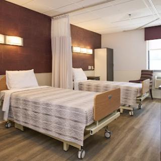 A spacious and well-lit patient room in a hospital, featuring two adjustable beds and a modern interior.