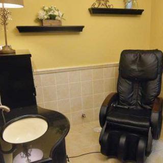 A cozy spa room featuring a black massage chair and elegant decor.
