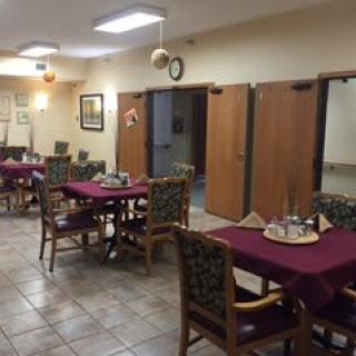 A cozy dining area with neatly arranged tables and chairs, featuring soft lighting and warm decor.