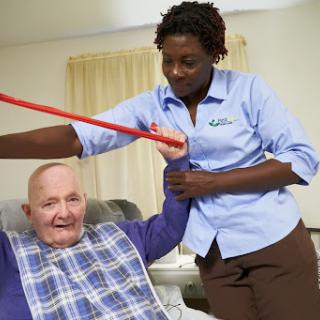 A caregiver assists an elderly person with rehabilitation exercises.