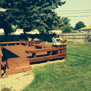 A sunny backyard with a wooden deck and surrounding lawn.