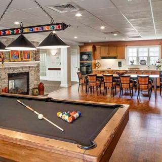 A spacious game room featuring a pool table, cozy fireplace, and an adjacent kitchen area.