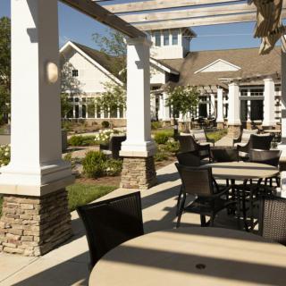 A sunny outdoor patio area with tables, chairs, and a pergola at a restaurant.